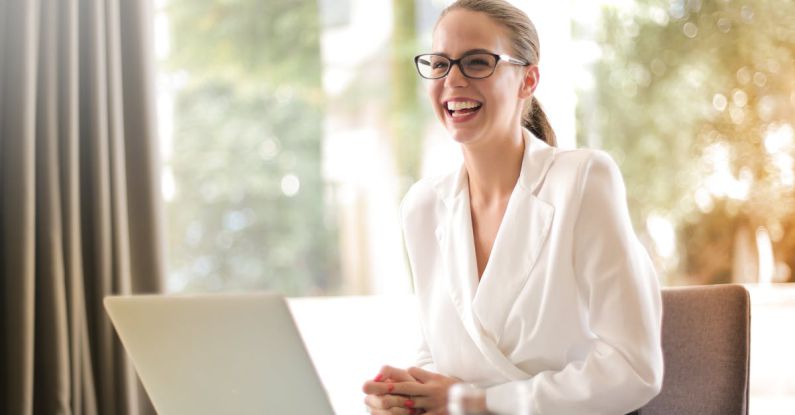Office Outfit - Laughing businesswoman working in office with laptop