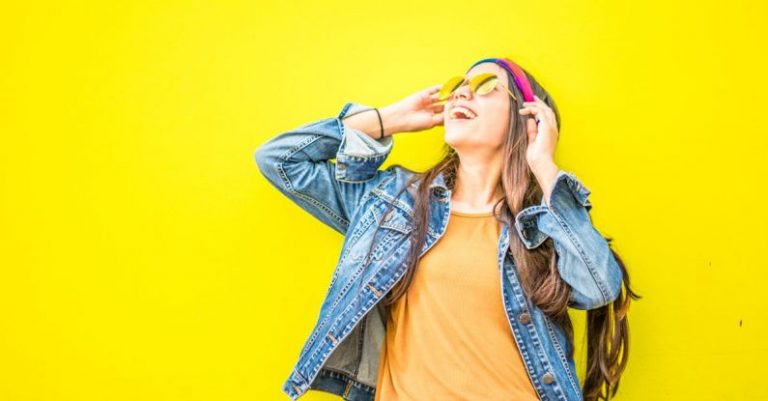 Fashion - Smiling Woman Looking Upright Standing Against Yellow Wall