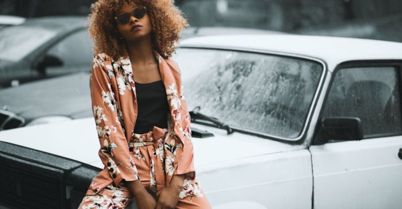 Street Style - Woman Wearing Brown Floral Print Coat and Pants Sitting on Car